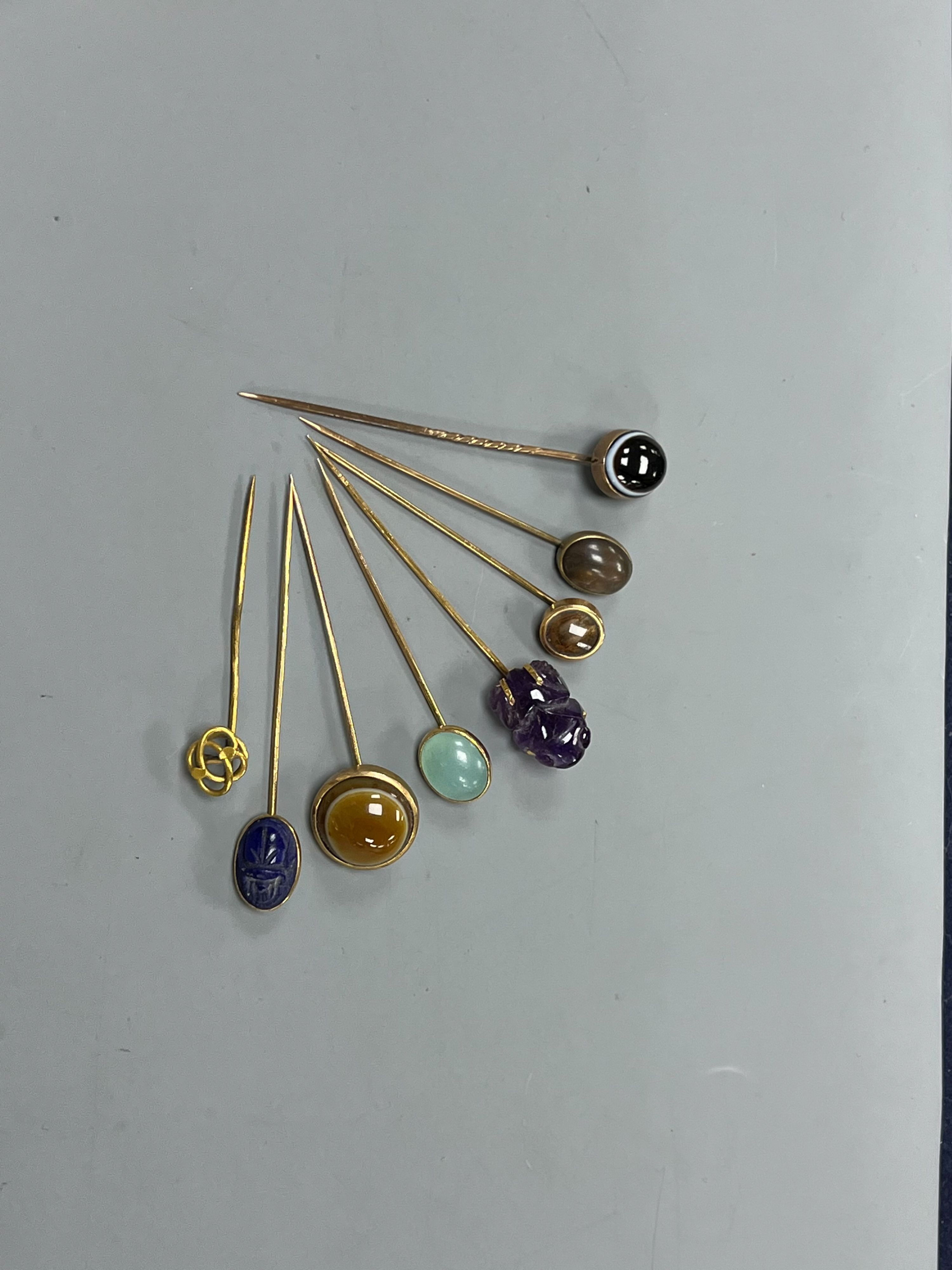 A small collection of eight assorted mainly yellow metal and chalcedony set stick pins, including Scarab, amethyst frog and banded agate